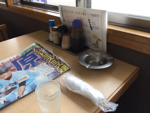 調味料とスポーツ新聞のあるさか本のテーブル
