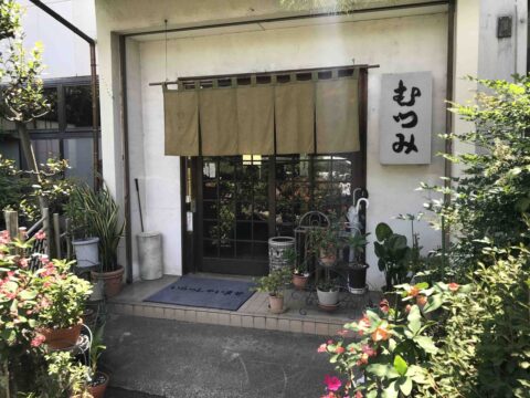 めん処むつみの外観。「むつみ」の暖簾と植木が並ぶ入口