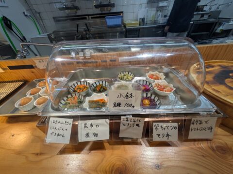日和製麺 春日井店の小鉢コーナー|各種100円、煮物やマリネが並ぶショーケース