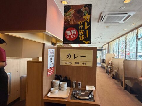 とんから亭のカレーかけ放題コーナー。「カレーかけ放題 無料サービス!」の垂れ幕と器、スパイスが並ぶ