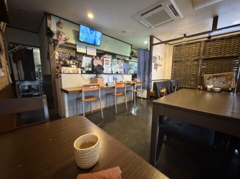 店内のテーブル席とカウンター席、手前にお茶とおしぼり