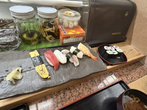 桜鮨のにぎり定食の完成形。下駄板に玉子、鮪、イカ、白身、海老などが一列に並び、別皿に細巻
