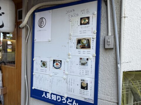 人見知りうどんの店外メニュー看板。2024年8月8日開店の手書き文字とロゴ