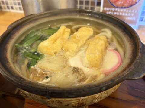 人見知りうどんの鍋焼きうどんのアップ。大きな油かす、卵焼き、かまぼこ、青菜