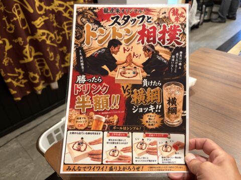龍虎朱のスタッフとトントン相撲の案内。勝ったらドリンク半額、負けたら横綱ジョッキ