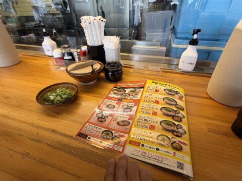 カウンター席。メニューと卓上調味料、サービスの九条ねぎ