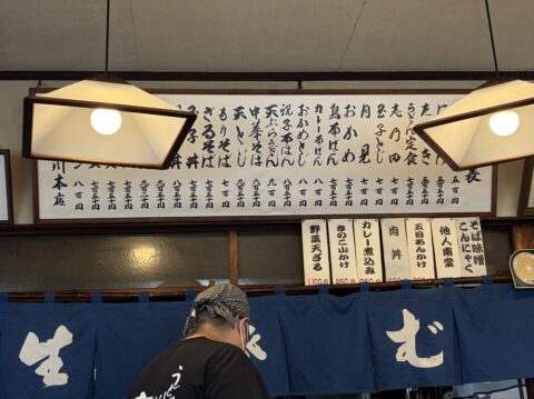 壁に掲げられた歴史ある献立表。おかめ、カレー南ばん、中華そばが縦書きで並ぶ