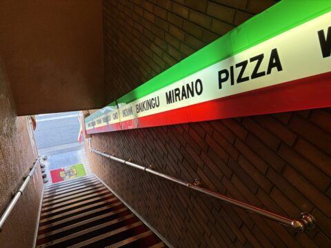 スパゲッ亭チャオ本店の階段。イタリアンカラーの看板にMIRANO、PIZZAなどのメニュー名が並ぶ
