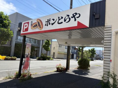 道路沿いに立つボンとらや本店の駐車場看板。ピレーネのイラスト入り