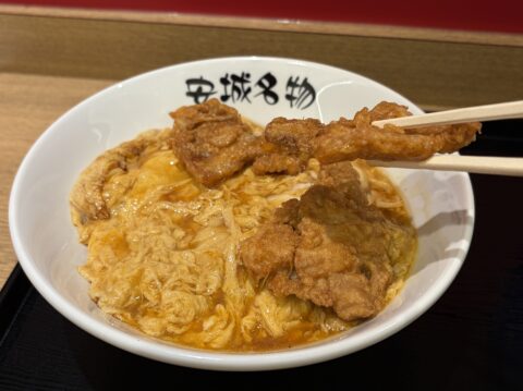 豚の唐揚げを箸で持ち上げたところ。丼には「安城名物」の文字
