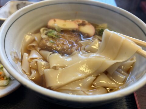 きしめんのアップ。油揚げ、かまぼこ、葱、花かつおが載る幅広の麺