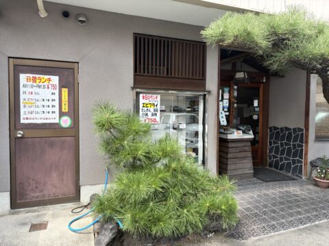 めん処大幸の入口まわり。松の植え込みとショーケース