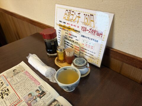 二日目の卓上。スポーツ新聞と日替ランチのPOP