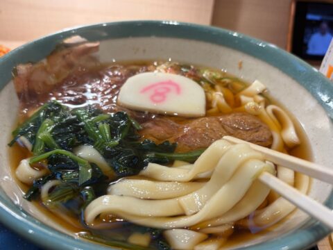「宮」の字入りのかまぼこと油揚げ、青菜の宮きしめん。平打ちの麺を箸で持ち上げる