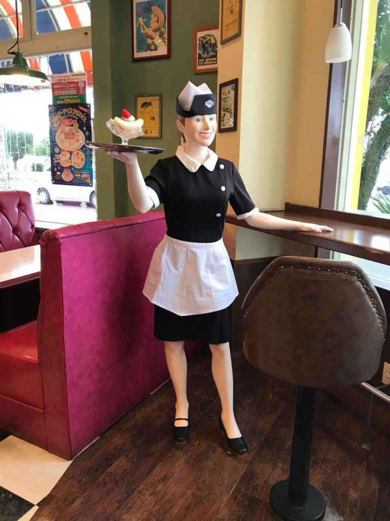 ブルーシール北谷店の店内。ウェイトレスのマネキンとピンクのソファ席