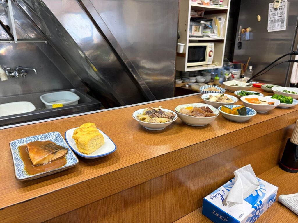 魚源食堂のカウンターに並ぶお惣菜。鯖の味噌煮、だし巻き、煮物