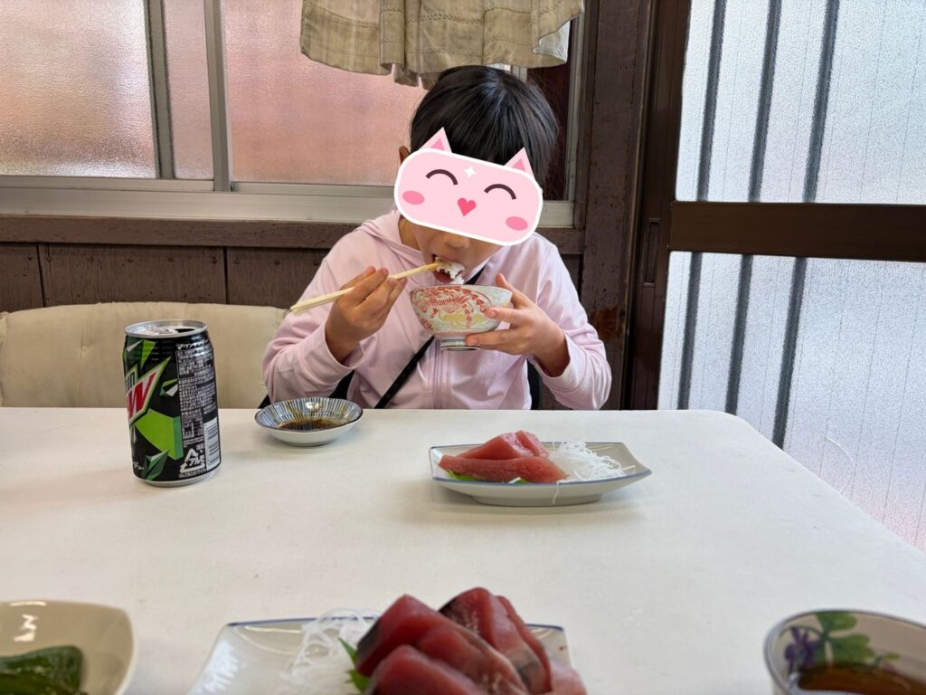 魚源食堂で鮪とご飯を頬張る子ども